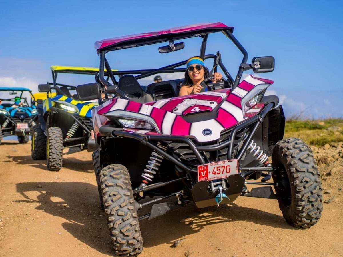 a group of people riding UTVs down a dirt path