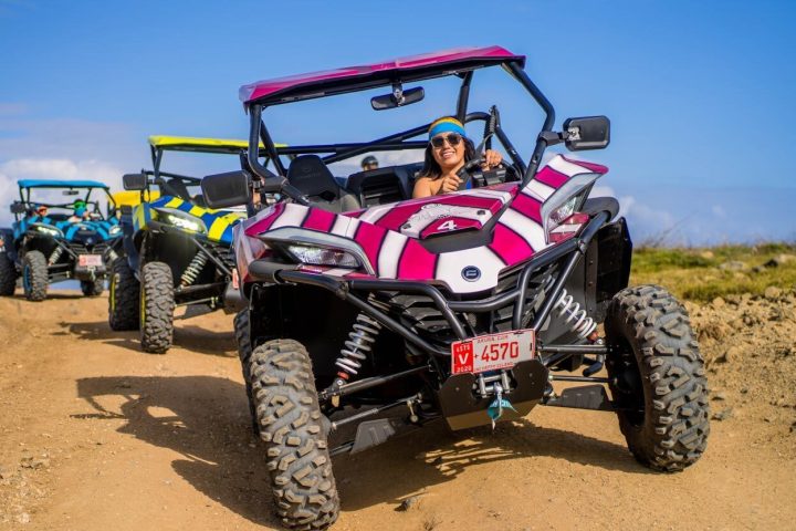 a group of people riding UTVs down a dirt path