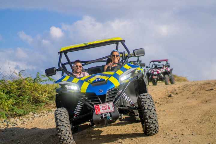 a group of people riding UTVs down a dirt road