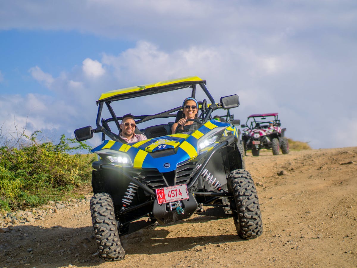 a group of people riding UTVs down a dirt road