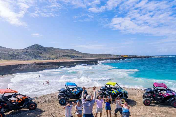 a group of people standing on a beach with UTVs behind them