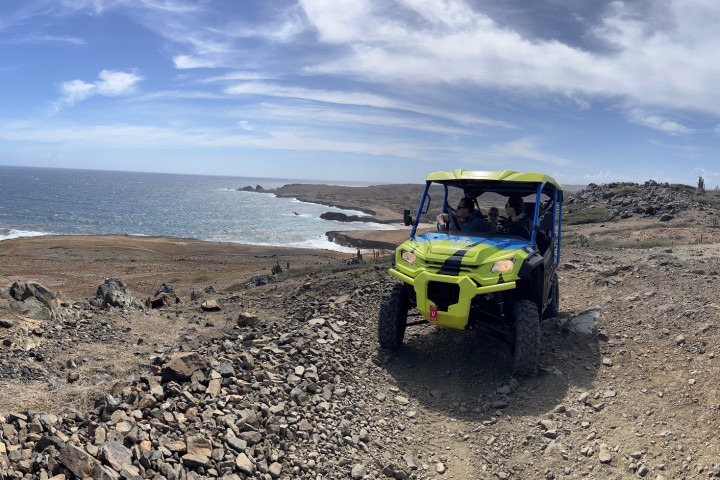 a group of people driving UTVs near an ocean