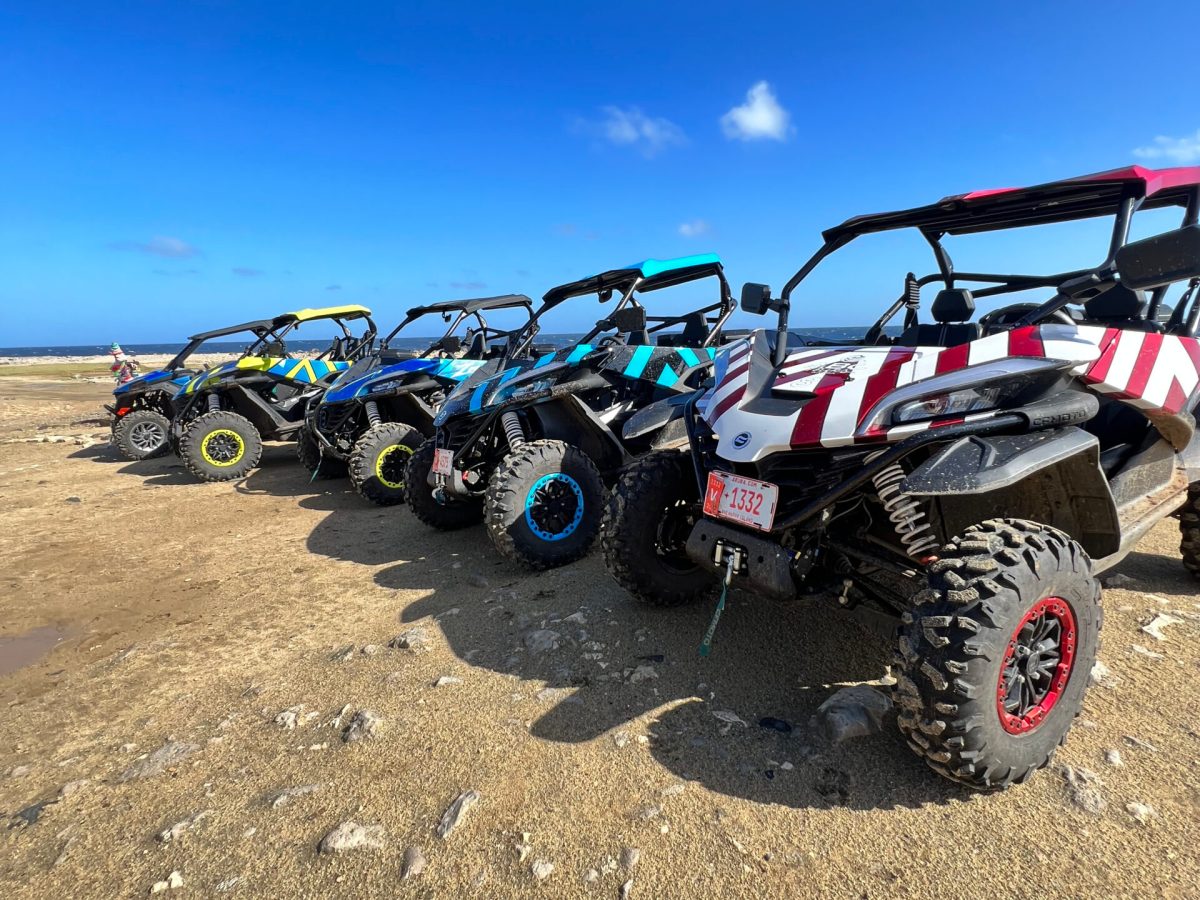 five UTVs lined up on a beach