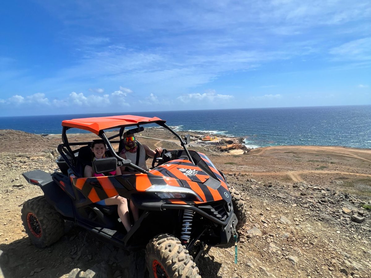two people in a UTV riding on the dirt next to the ocean